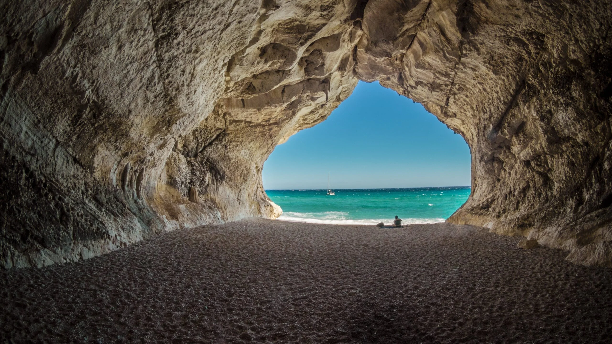 A beach framed by a rock arch on the Greek coast
